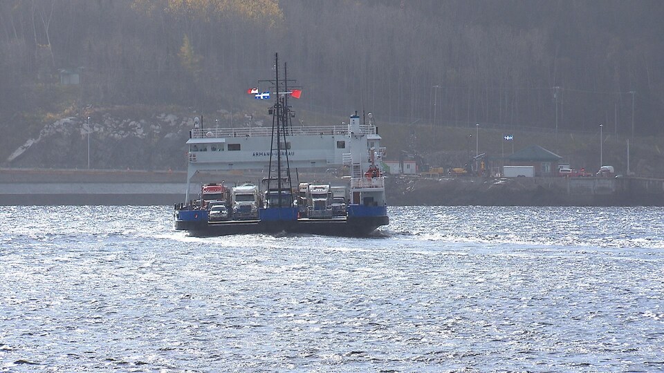 Un traversier flotte sur l'eau et semble rempli de véhicules lourds.