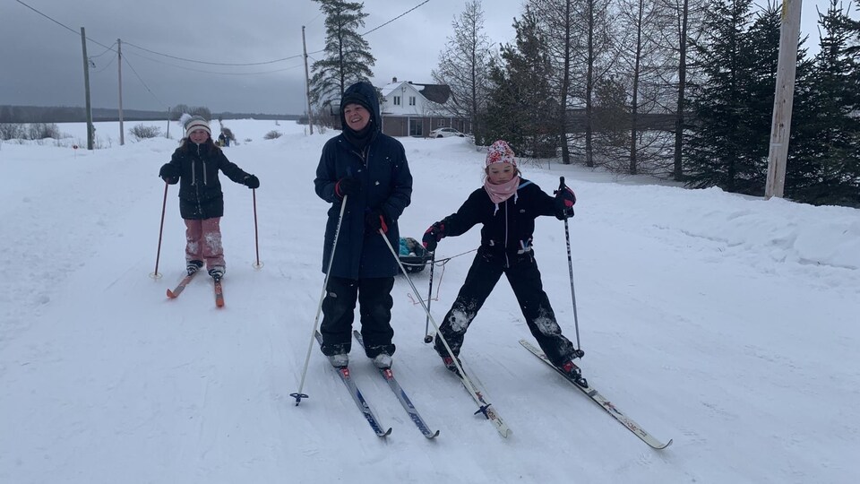 Des élèves et leur enseignant en ski de fond sur un chemin enneigé.
