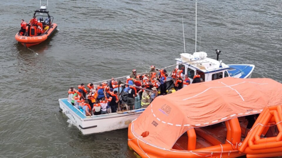Des passagers sont évacués du traversier dans un bateau de sauvetage.