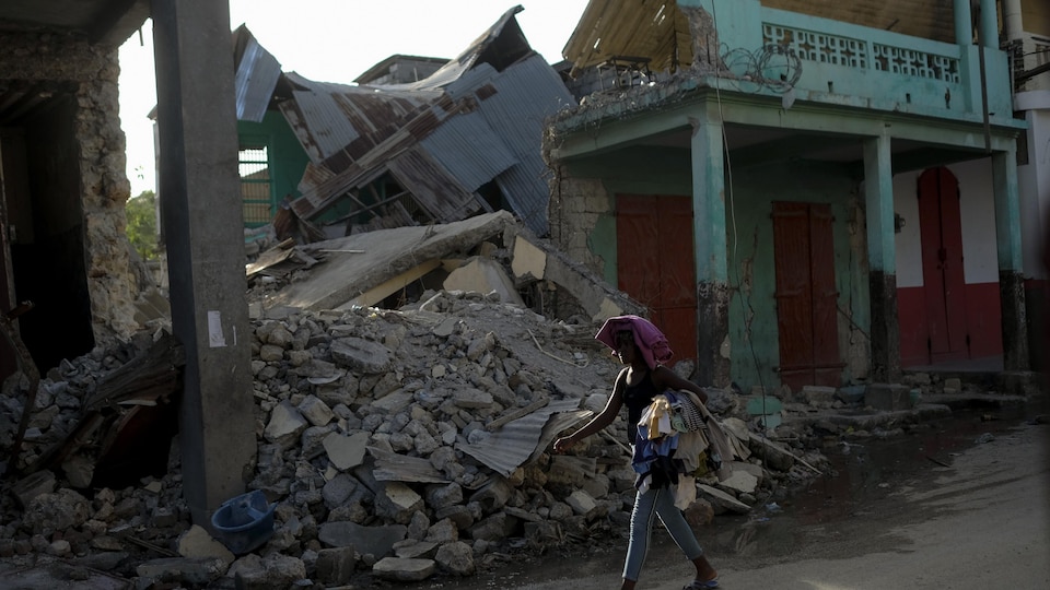 A woman walks past a collapsed building in Jeremie, Haiti, Wednesday, Aug. 18, 2021, four days after the city was struck by a 7.2-magnitude earthquake. (AP Photo/Matias Delacroix)