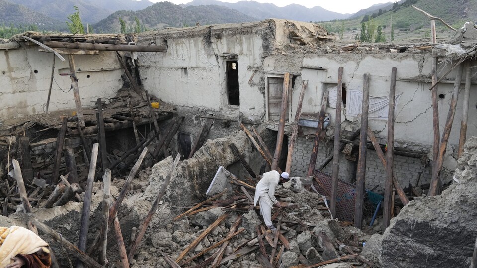 Un Afghan marche dans les décombres d'une maison détruite.