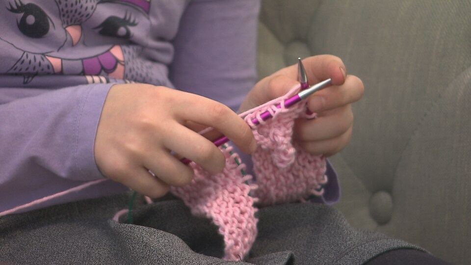 Une petite fille fait du tricot.
