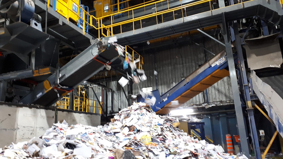 Une machine qui tri du papier. À l'avant, on trouve une immense quantité de papier.