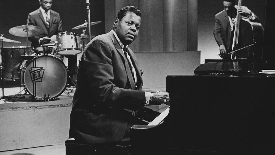 Dans un studio de télévision, Oscar Peterson, assis au piano, avec en arrière-plan Ed Thigpen à la batterie et Ray Brown à la contrebasse.