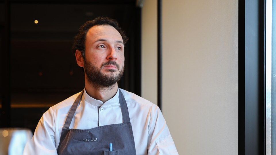Le chef étoilé Jean-Vincent Troiano assis dans une table de son restaurant et regarde vers la fenêtre. 
