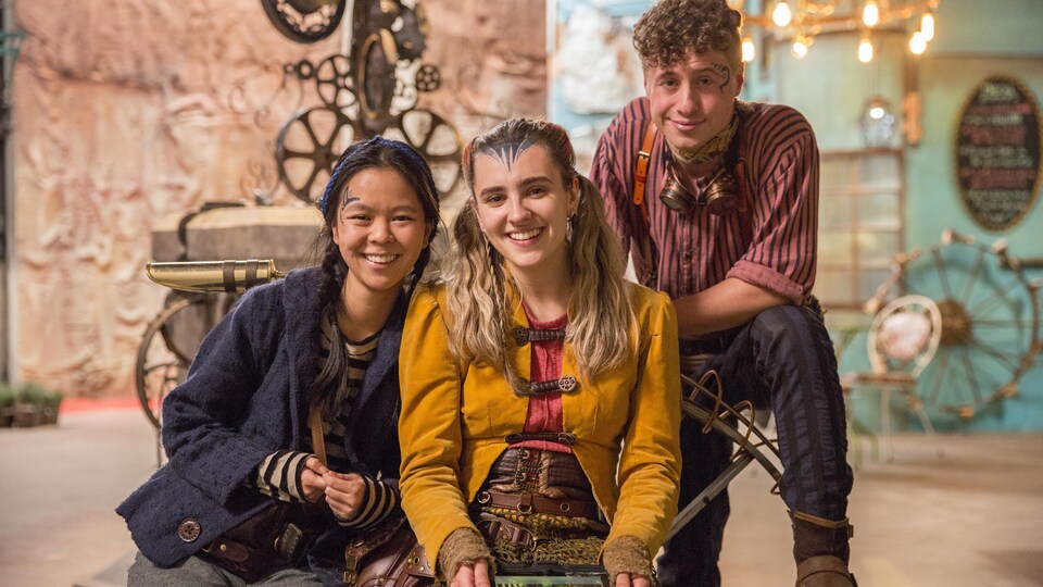 Les trois personnages de la série Makinium sourient à la caméra.