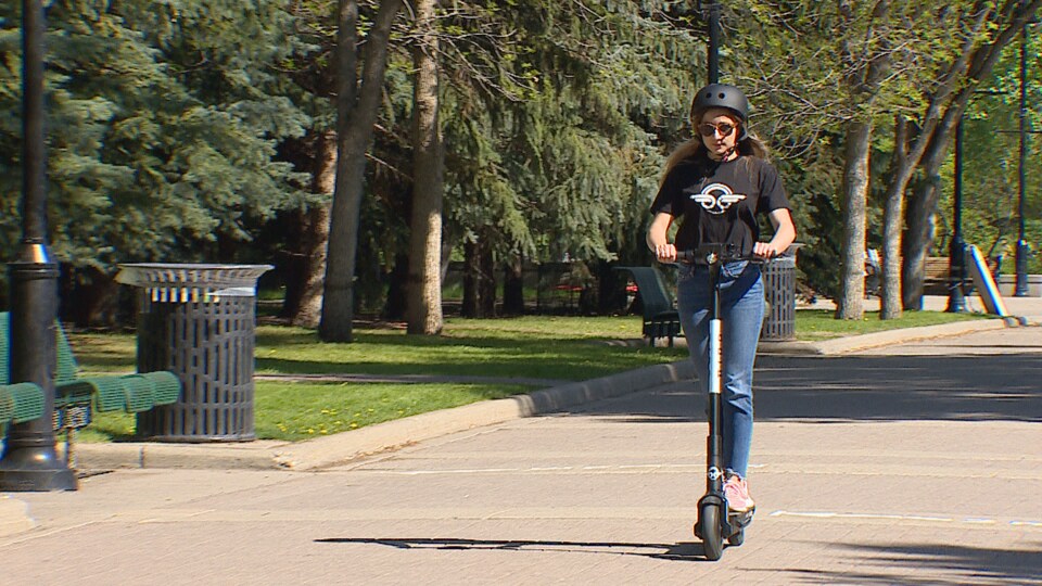 Une femme sur une trottinette électrique.