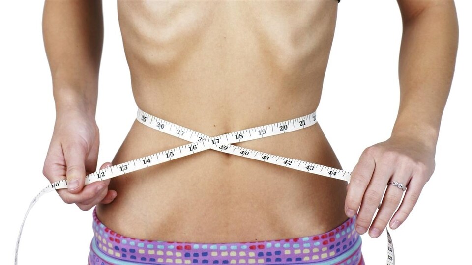 Une fille mesure son tour de taille.
