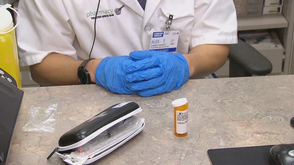 Une trousse de naloxone sur une table dans une pharmacienne portant des gants en latex.