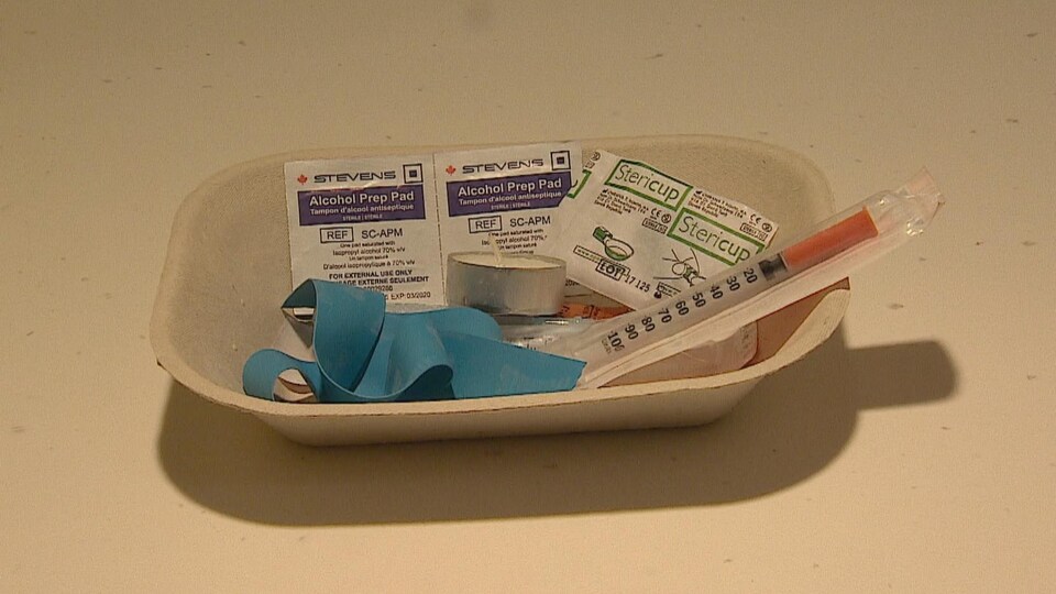 Une trousse avec une aiguille stérile, des tampons d'alcool antiseptique et une bande élastique.