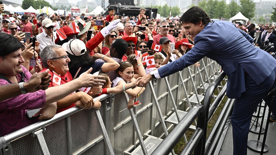 Justin Trudeau serre la main d'un enfant membre du public. 