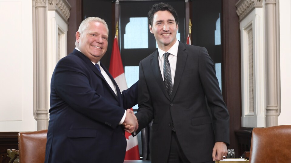 Justin Trudeau et Doug Ford se serrent la main, souriants.