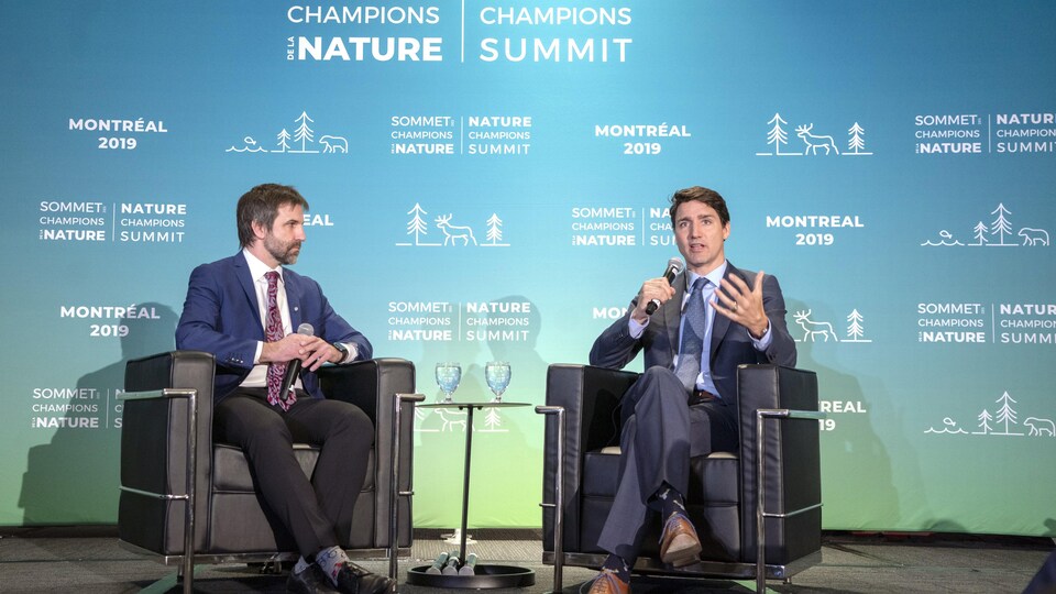 Steven Guilbeault et Justin Trudeau sont assis ensemble et discutent.