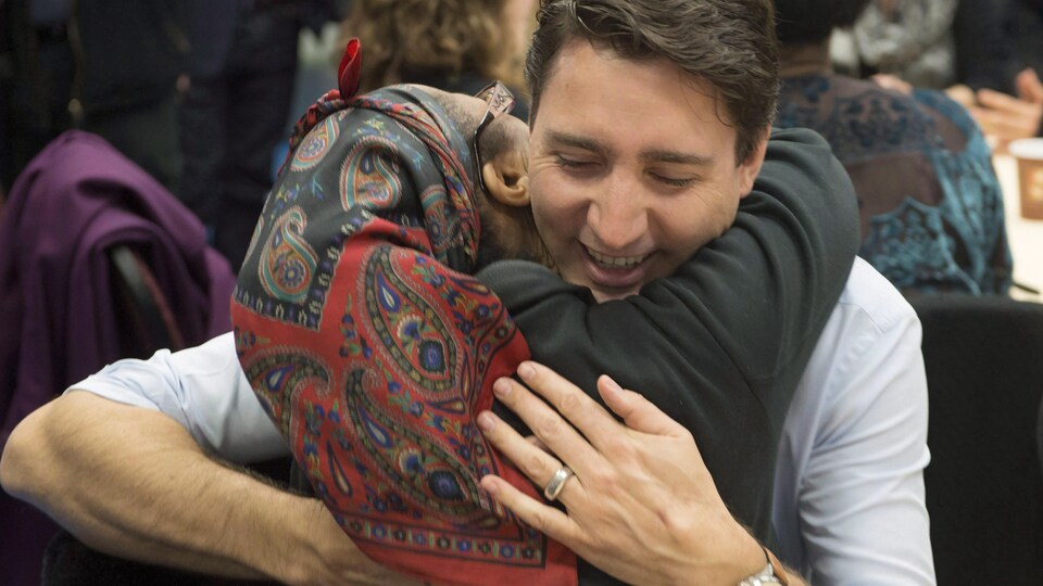 Le premier ministre Justin Trudeau est photographié alors qu'il enlace une femme migrante portant un foulard sur sa tête.