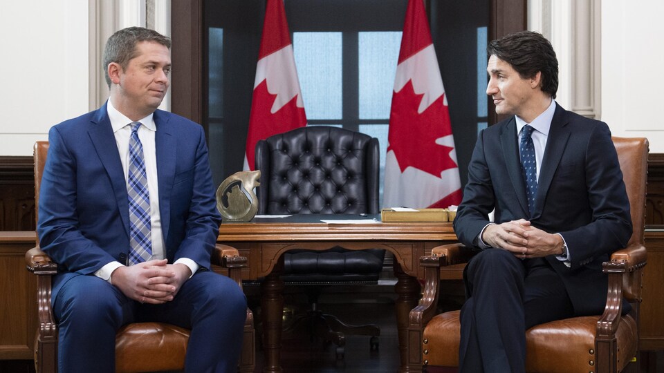 Justin Trudeau et Andrew Scheeer, assis, se regardent.