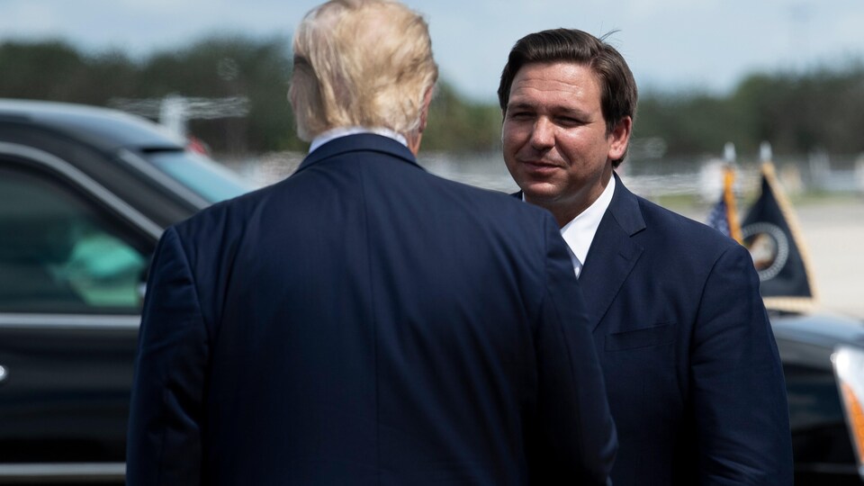 Ron DeSantis regarde Donald Trump en souriant.