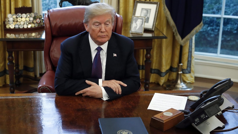 Donald Trump assis au bureau ovale. 