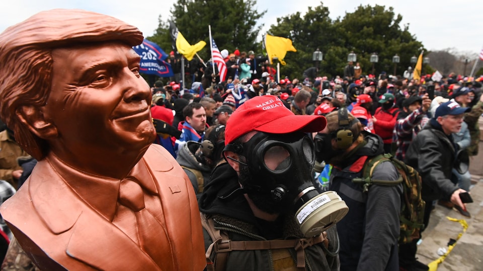 Un partisan de Donald Trump porte un masque à gaz et tient un buste de l'ancien président durant l'assaut du Capitole, à Washington, le 6 janvier 2021.
