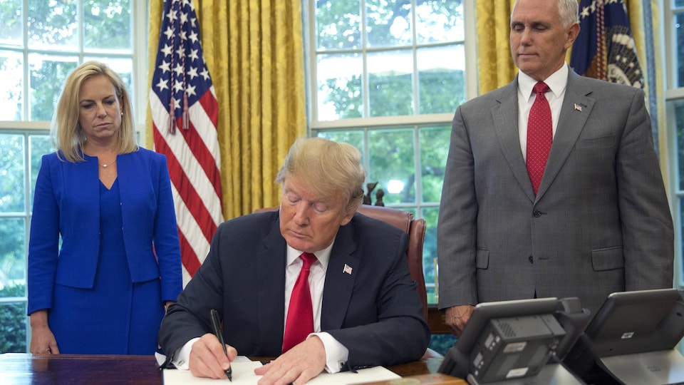 Le président américain Donald Trump signe le décret avec, derrière lui, la secrétaire à la Sécurité intérieure Kirstjen Nielsen et le vice-président Mike Pence.