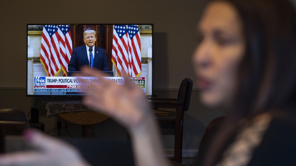 Une femme travaille à son poste tout en regardant le discours d'adieu du président Donald Trump sur la chaîne Fox News.