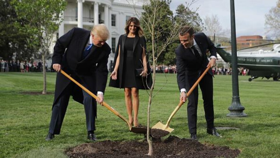 Donald Trump et Emmanuel Macron tiennent une pelle.