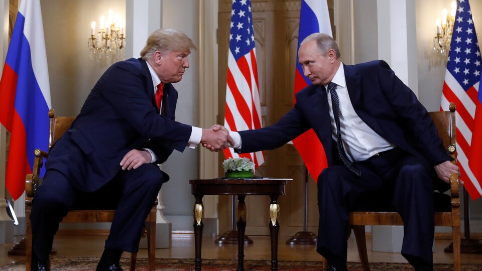MM. Trump et Poutine se penchent l'un vers l'autre pour se serrer la main.