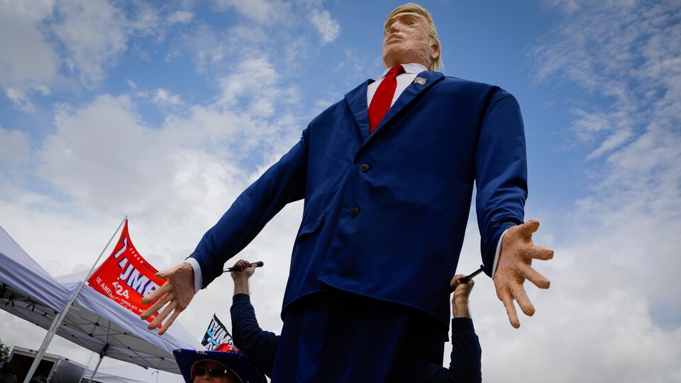 Un homme manipule un mannequin géant représentant Donald Trump lors d'un rallye à Sarasota, en Floride.