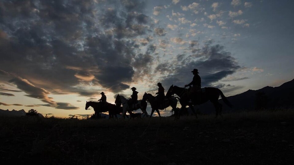 Des cowboys de la Première Nation Xeni Gwet'in dans la vallée de Nemaiah au coucher du soleil.