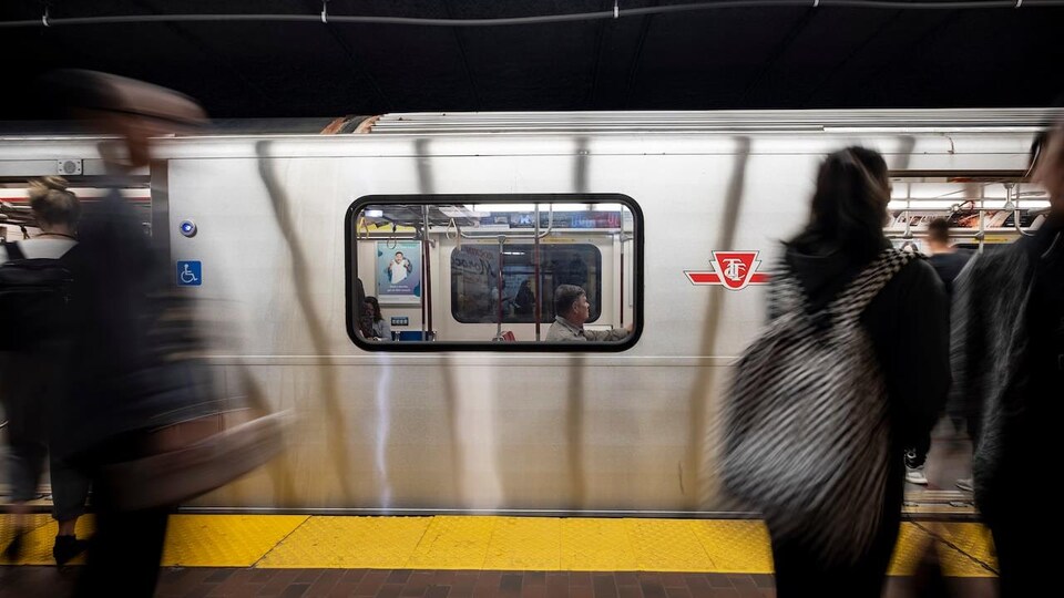 Des personnes débout devant un métro à Toronto.
