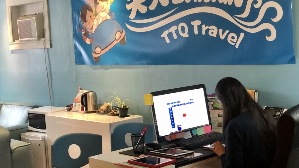 Une employée d'une agence de voyages devant son ordinateur.