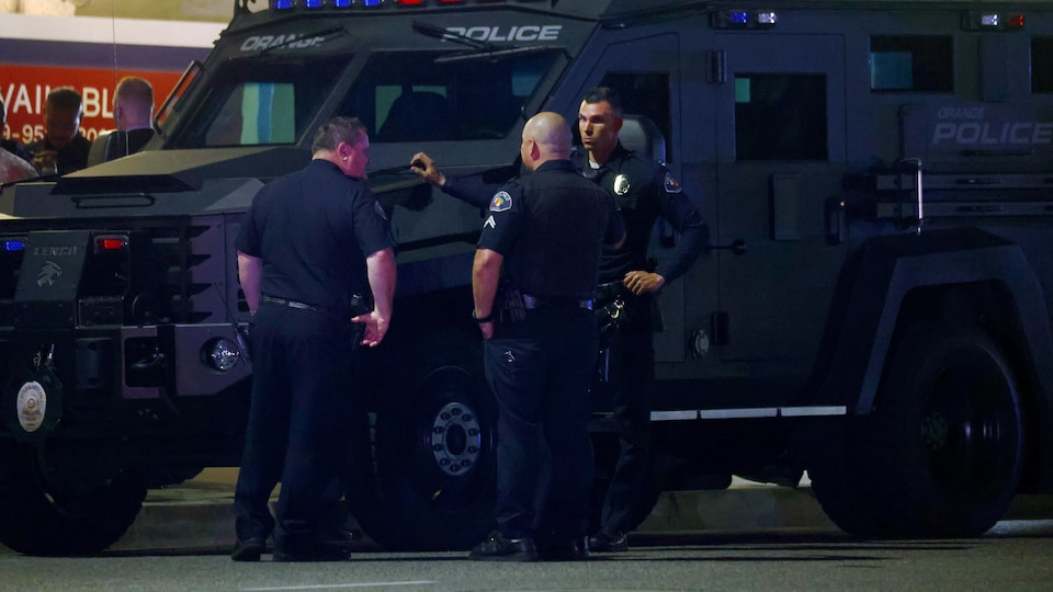 Des policiers discutent devant un camion blindé.