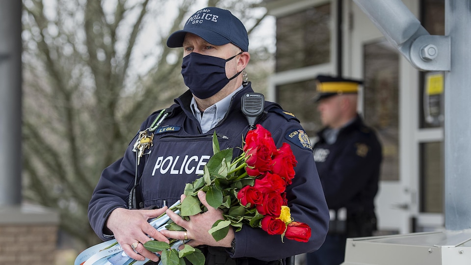 Un policier en uniforme tenant un bouquet de roses.