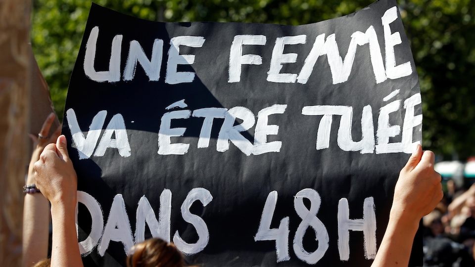 Une personne porte une pancarte où il est écrit qu'« une femme va être tuée dans 48 heures ».