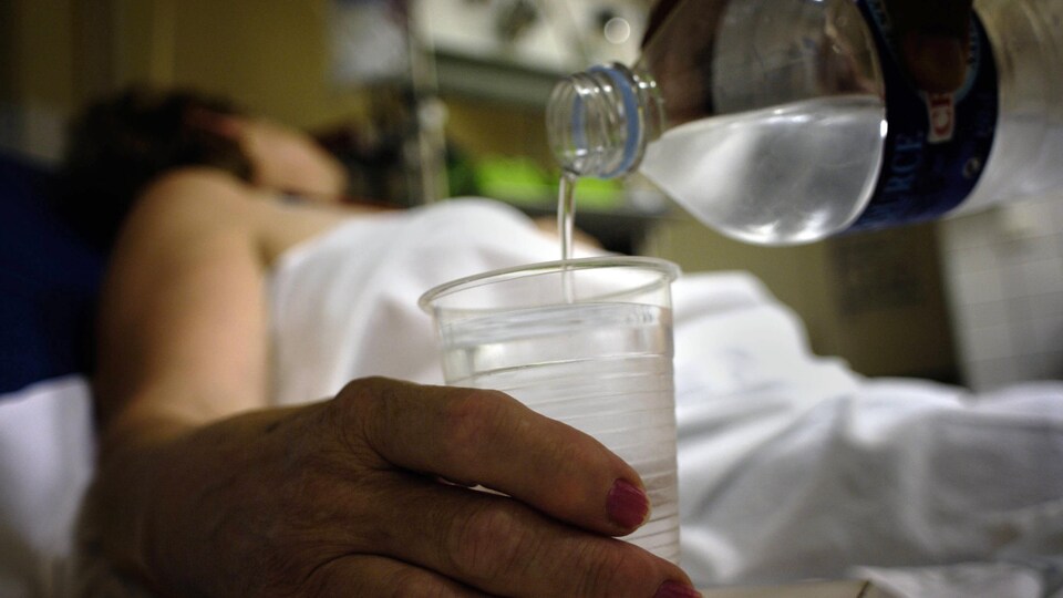Un infirmier remplit le verre d'une patiente.