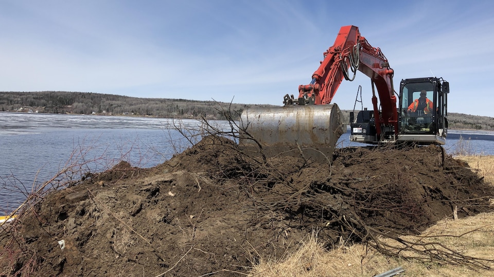 Une pelle mécanique retire les terres contaminées près du lac.