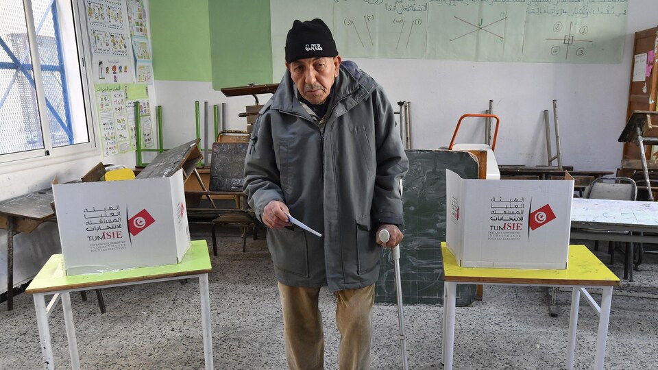 Un homme s'appuie sur une béquille dans un bureau de vote.