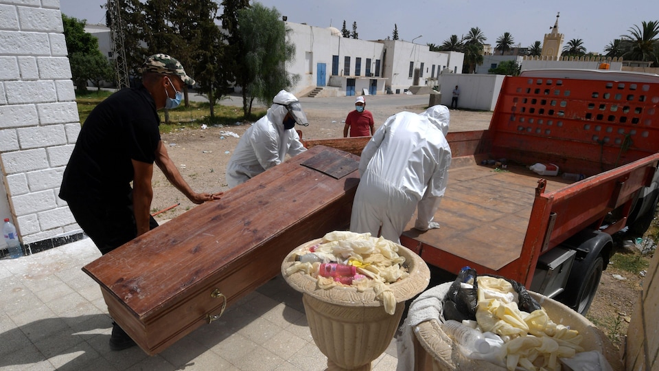 Staff carry a grave in a truck