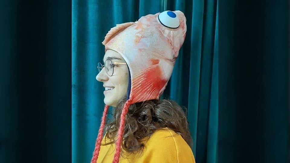 Une jeune femme porte une tuque en forme de tête de poisson.