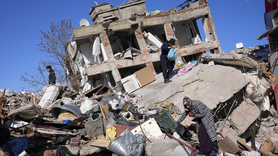 Des personnes recherchent leurs affaires dans un bâtiment effondré à Kahramanmaras, dans le sud de la Turquie.