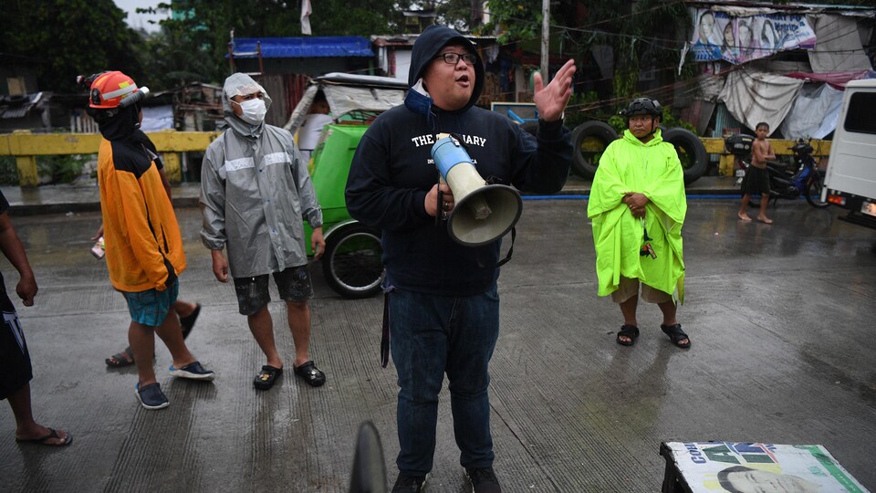 Une personne tient un mégaphone sous la pluie.