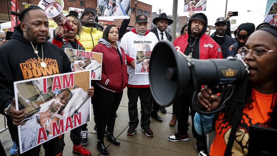 Des membres de la communauté afro-américaine brandissant une photo de la victime lors de son hospitalisation.