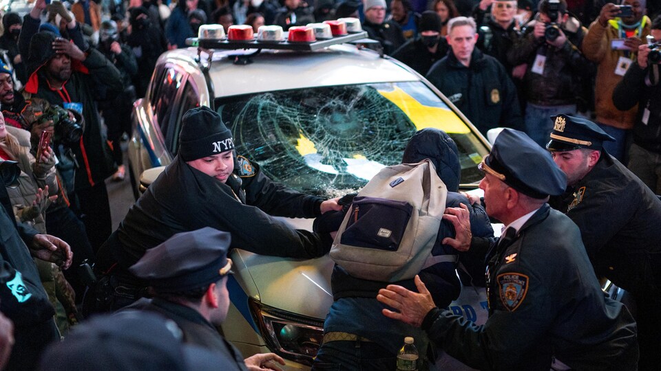 Des policiers retiennent un manifestant sur un véhicule de police, le jour de la diffusion d'une vidéo montrant des policiers en train de frapper Tyre Nichols, le jeune Noir mort trois jours après avoir été arrêté au volant lors d'un contrôle routier par des policiers de Memphis, à New York, aux États-Unis, le 27 janvier 2023.