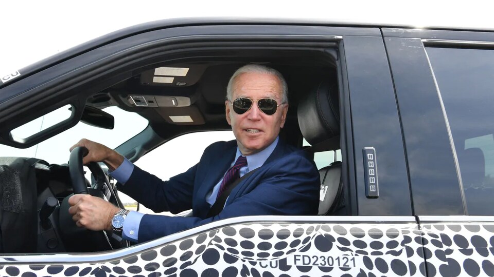 Le président américain Joe Biden au volant d'une voiture, des lunettes sur le nez.