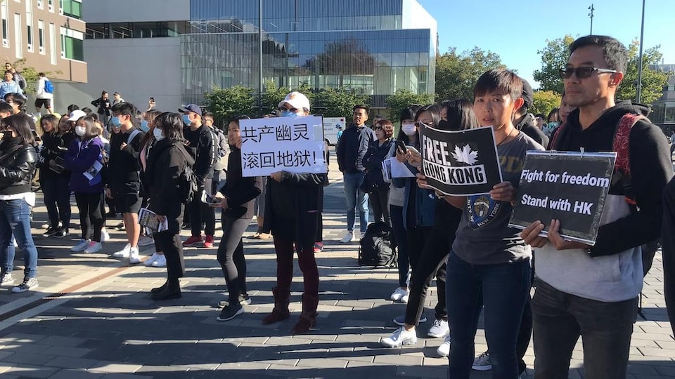 Une vingtaine d'étudiants sont rassemblés à l'extérieur sur le campus de l'Université de la Colombie-Britannique et brandissent des pancartes pro-Hong Kong.