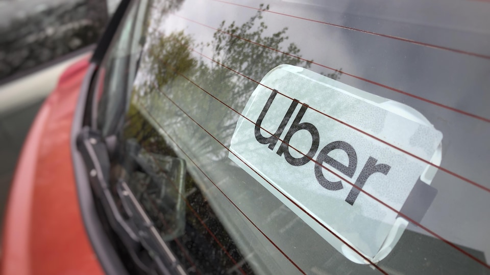 Un autocollant identifiant une voiture Uber, dans la lunette arrière.