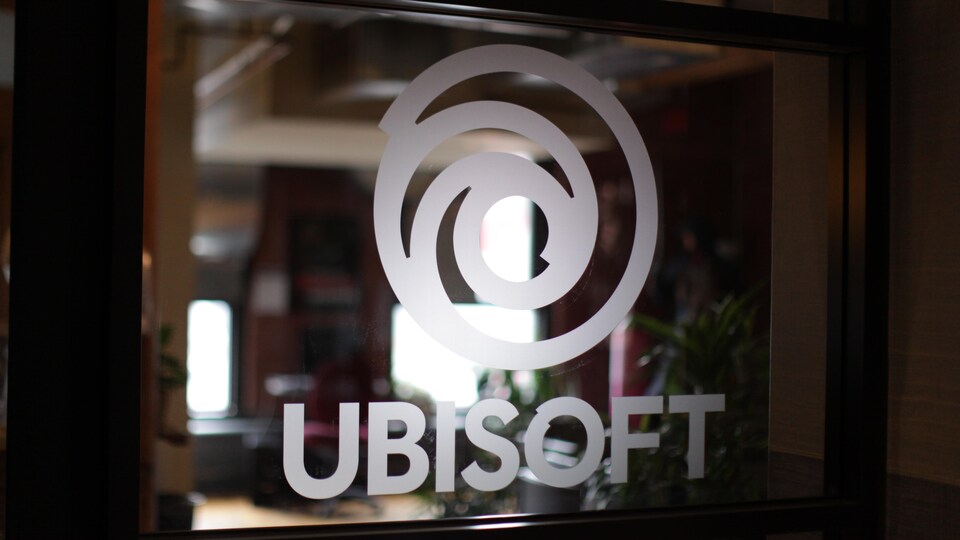Une vitre donnant sur la réception d'Ubisoft Montréal sur laquelle est dessiné le logo de la compagnie