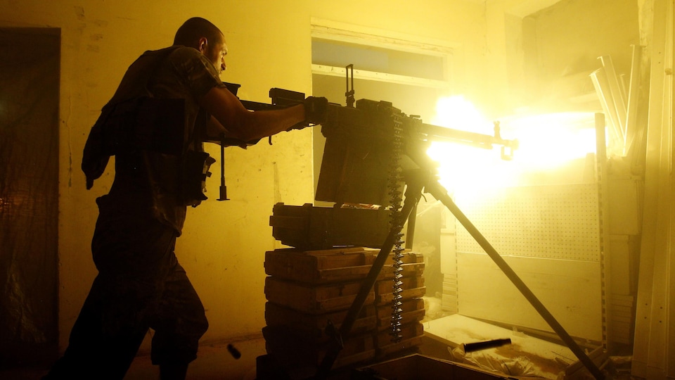 A Ukrainian militant fires a machine gun from inside his shelter.