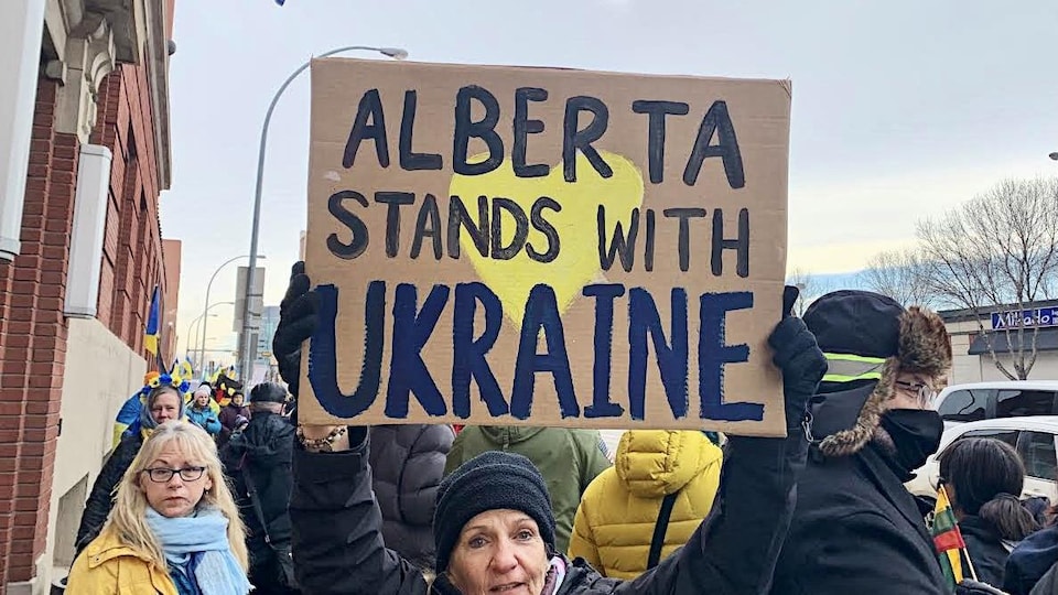 Une manifestante tient une affiche qui dit que l'Alberta soutient l'Ukraine.