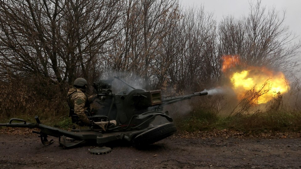 A soldier fires an automatic cannon.