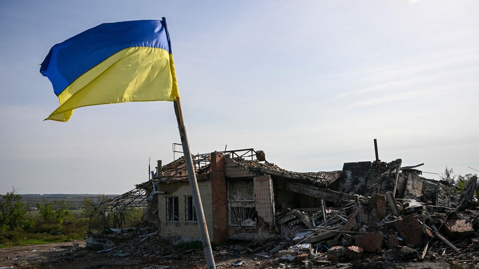 Un drapeau ukrainien flotte devant une maison détruite près d'Izioum, dans l'est de l'Ukraine, le 1er octobre 2022.
